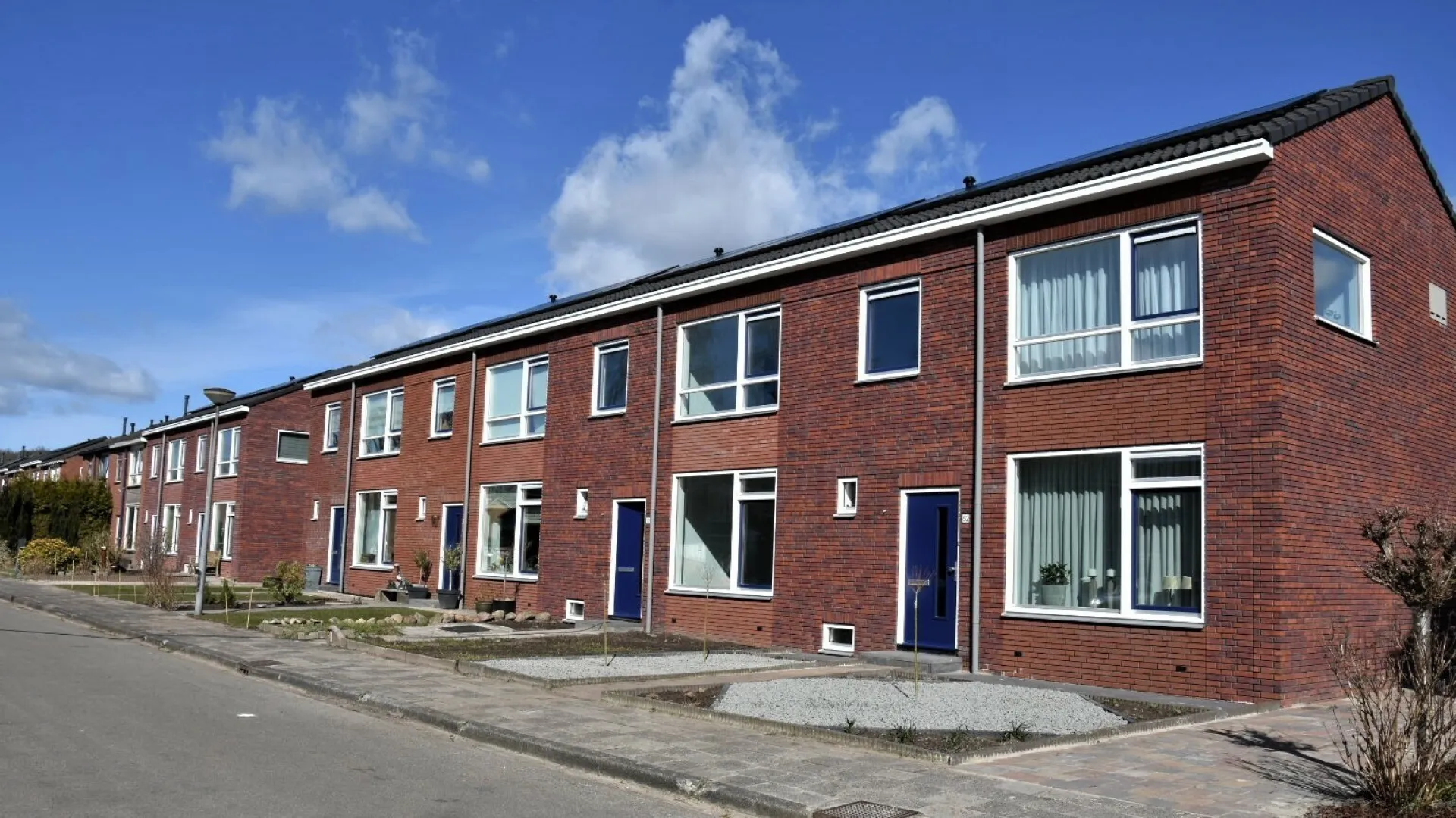 Rij van bakstenen huizen onder een blauwe hemel.