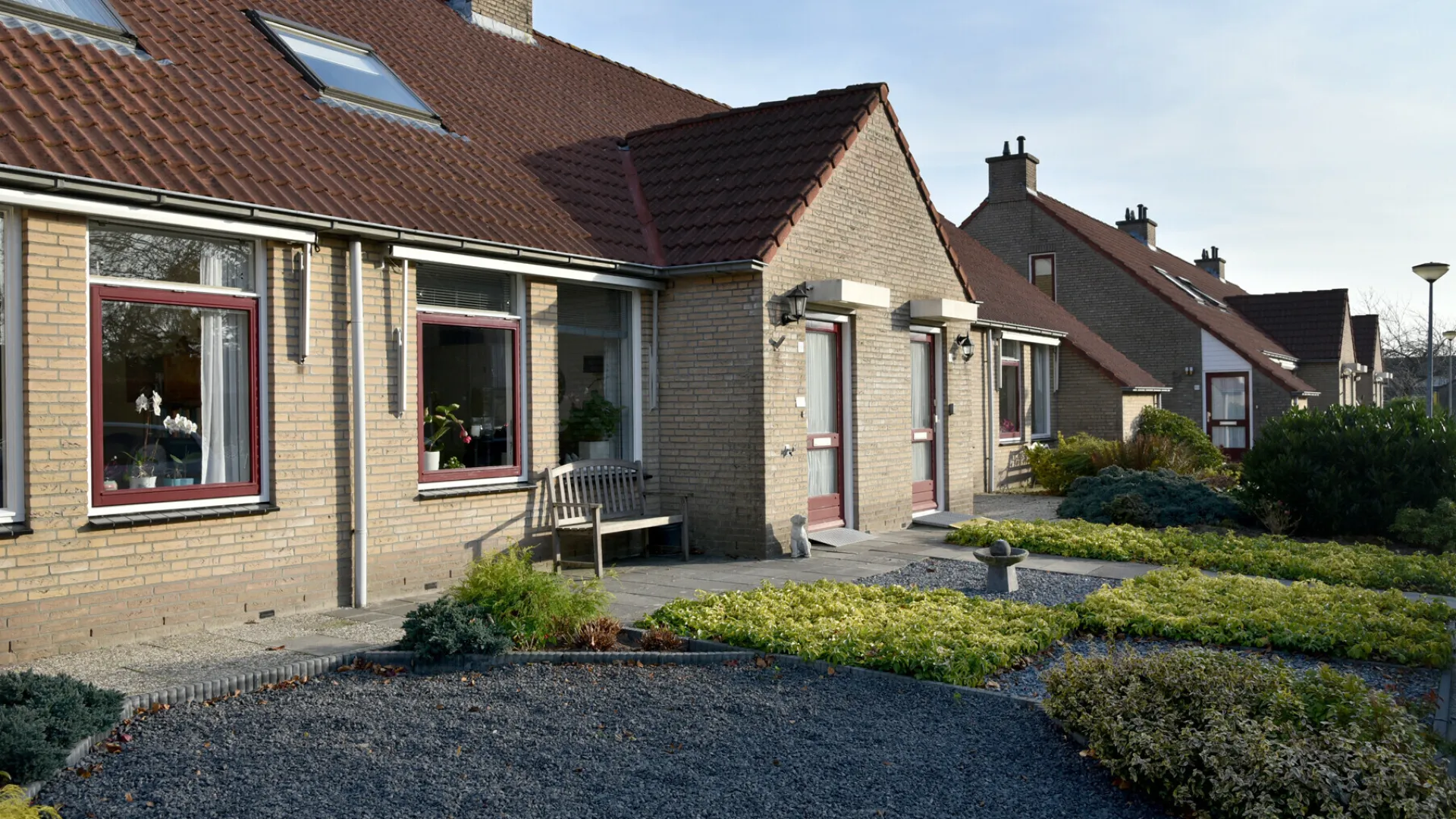 Rijtjeshuis met goed onderhouden voortuin en rode daken.