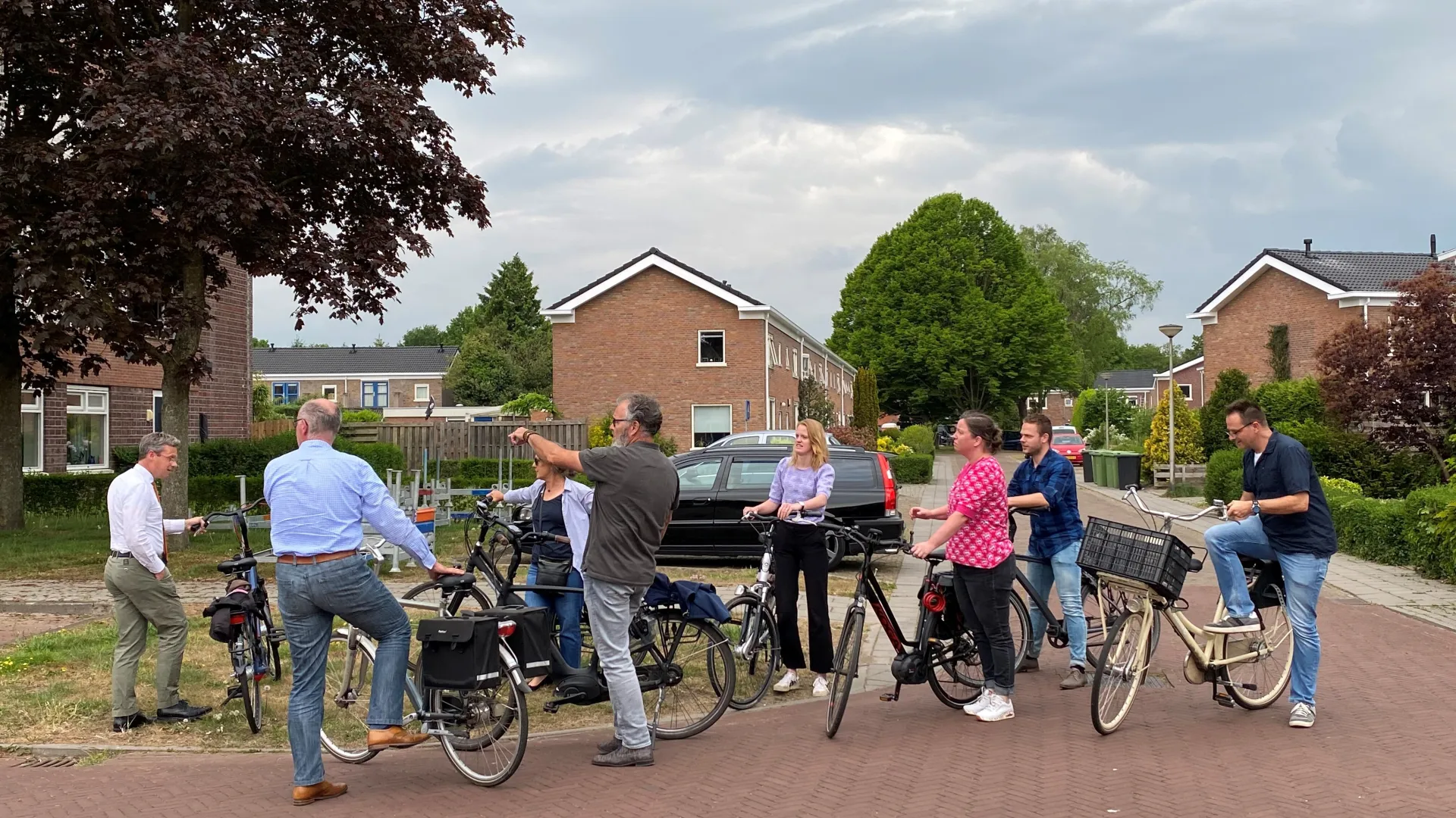 Mensen staan en praten bij hun fietsen in een woonwijk.