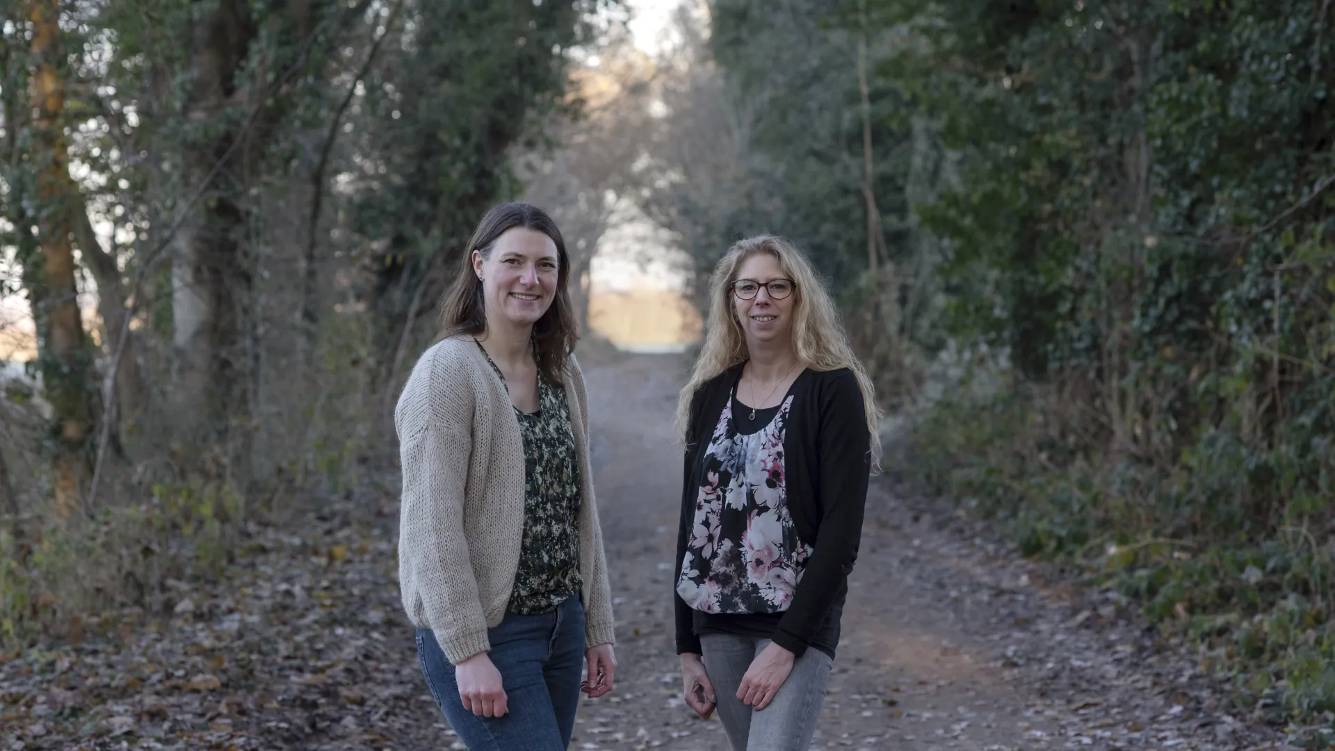 Twee vrouwen staan op een bosweg.