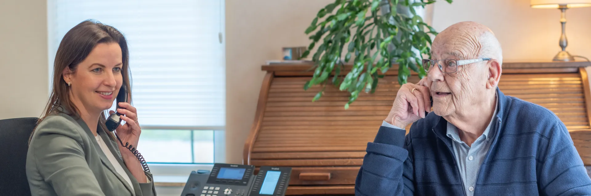 Een vrouw en een oudere man hebben een gesprek op kantoor.