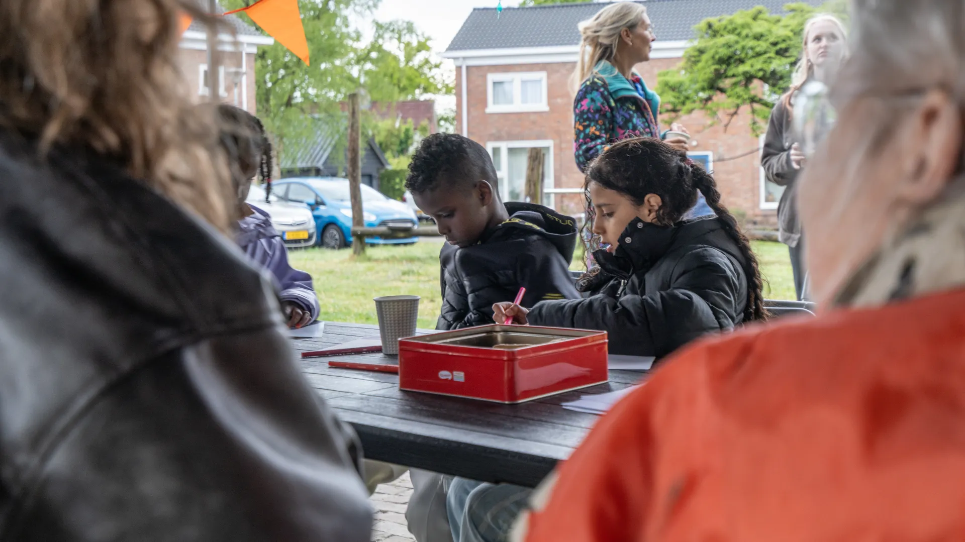 Kinderen knutselen aan een tafel buiten.