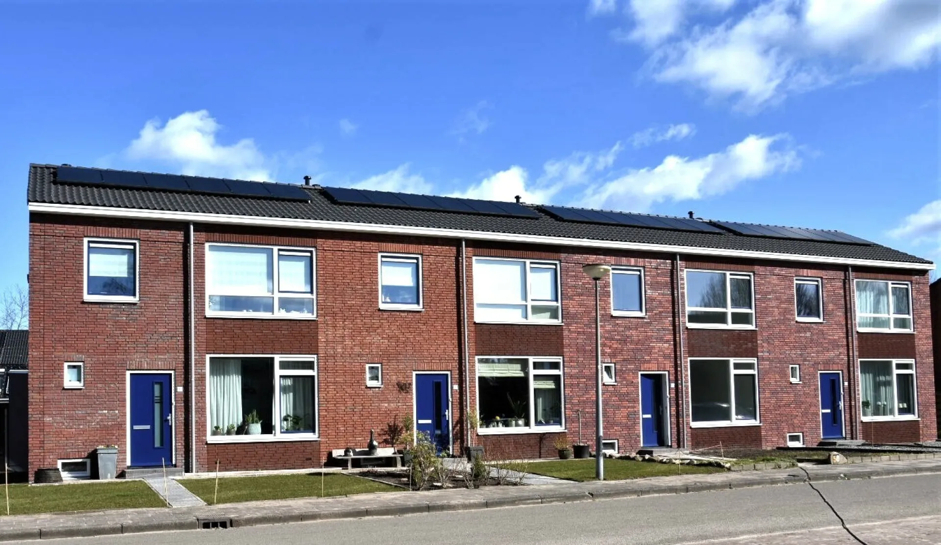 Een rij van rode bakstenen huizen onder een blauwe lucht.