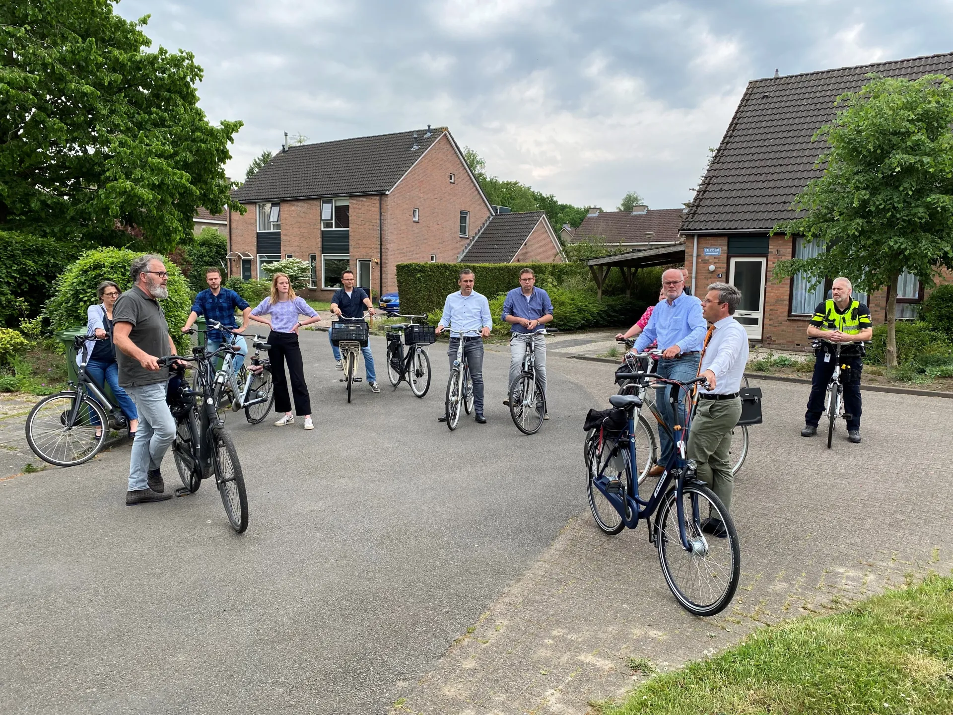 Mensen op fietsen poseren voor een foto in een woonwijk.